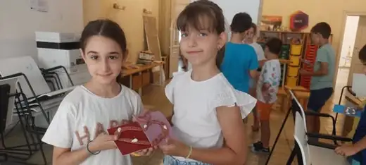 Две момичета показват украсено глинено сърце в творческата зала