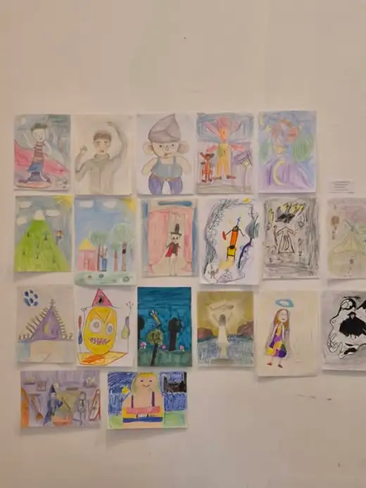 Стена, покрита с малки цветни детски рисунки на фигури