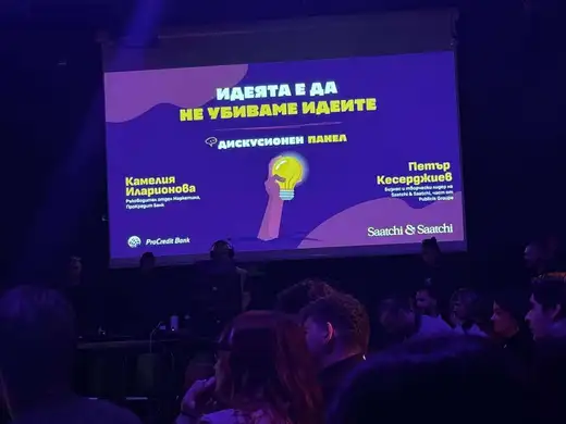 Екран със заглавие „Идеята е да не убиваме идеите“ и имена на двама участници в дискусионен панел, пред него публика.