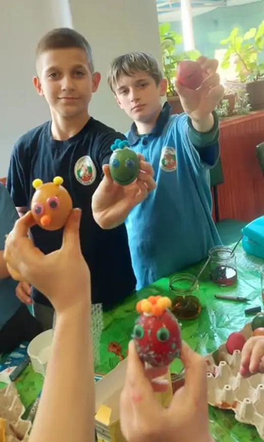 Двама ученици показват яйца, превърнати в фигурки с очички и рогца.