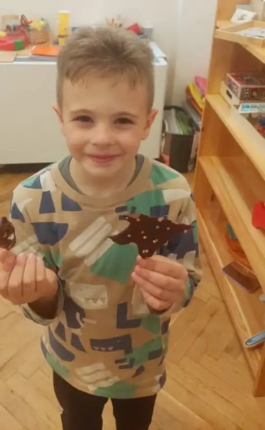 Момче държи в двете си ръце шоколадови фигурки с посипка.