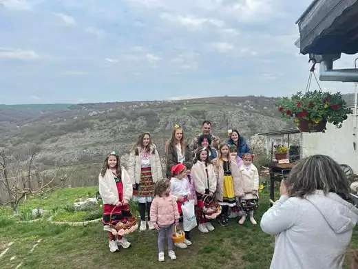 Деца и възрастни в носии позират за снимка на ръба на хълм, а жена ги снима.