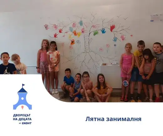 Деца пред стена с нарисувано дърво от цветни детски длани