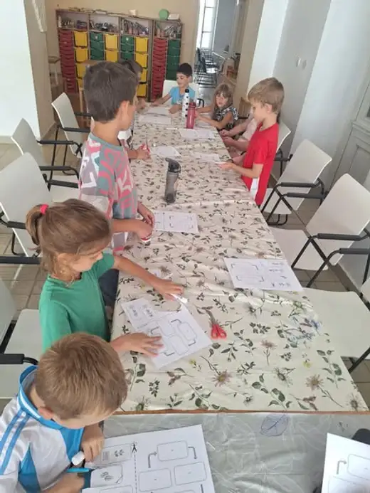 Деца попълват работни листове по дългата маса