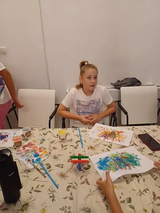 Момиче до маса с нарисувани цветни чудовища