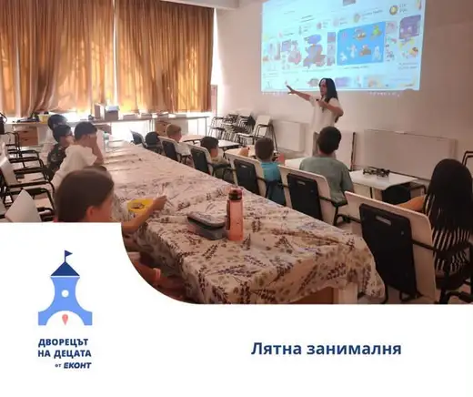 Жена показва презентация на екран пред деца, седнали на дълга маса.