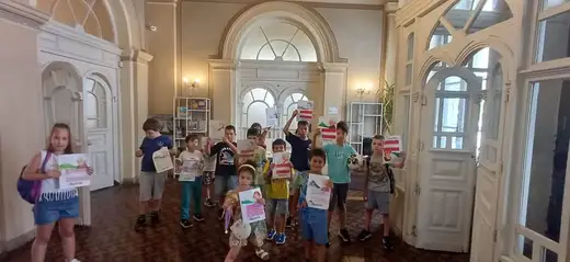 Група деца в голяма зала държат листове в ръцете си