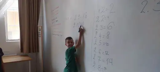 Момче пише таблицата за умножение на бяла дъска