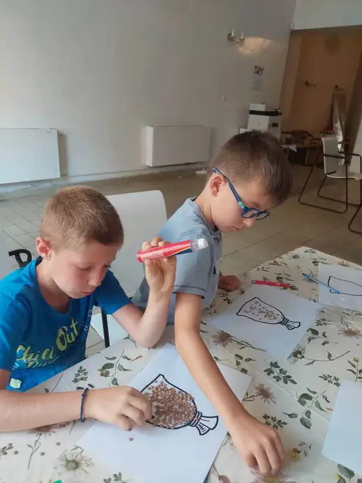Двама момчета оцветяват рисунки на маса.