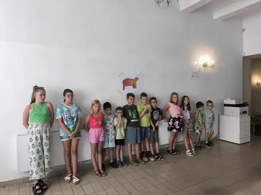 Деца, наредени в редица до стената на залата.