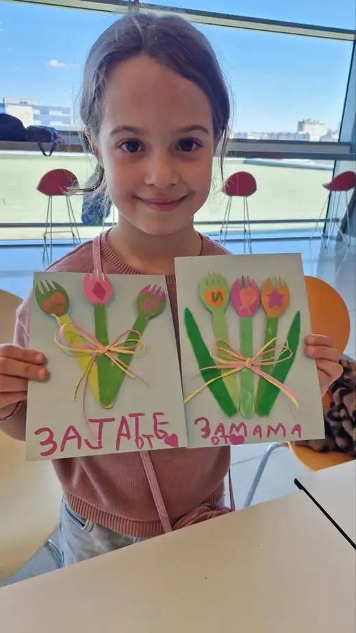 Усмихнато момиче държи две готови картички с хартиени лалета.