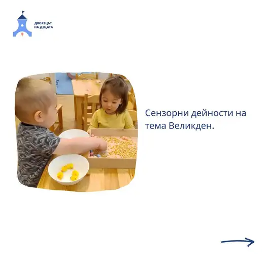 Две деца седят край дървена маса с табла, пълна с царевица, цветни яйца и жълти пиленца в купичка.