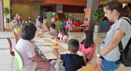 Деца и родители рисуват на дълга маса в мола