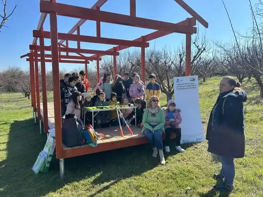 Деца около дървената конструкция на зелената класна стая в градината.