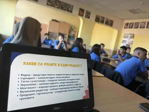 Лаптоп със слайд „Какви са ролите в един подкаст?“ пред клас ученици.