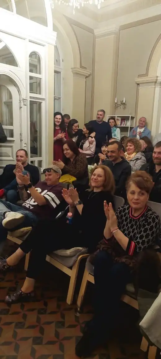 Препълнена зала със зрители, които ръкопляскат.