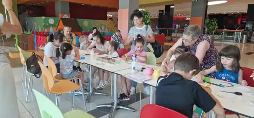 Деца и родители работят на дълги маси в мола