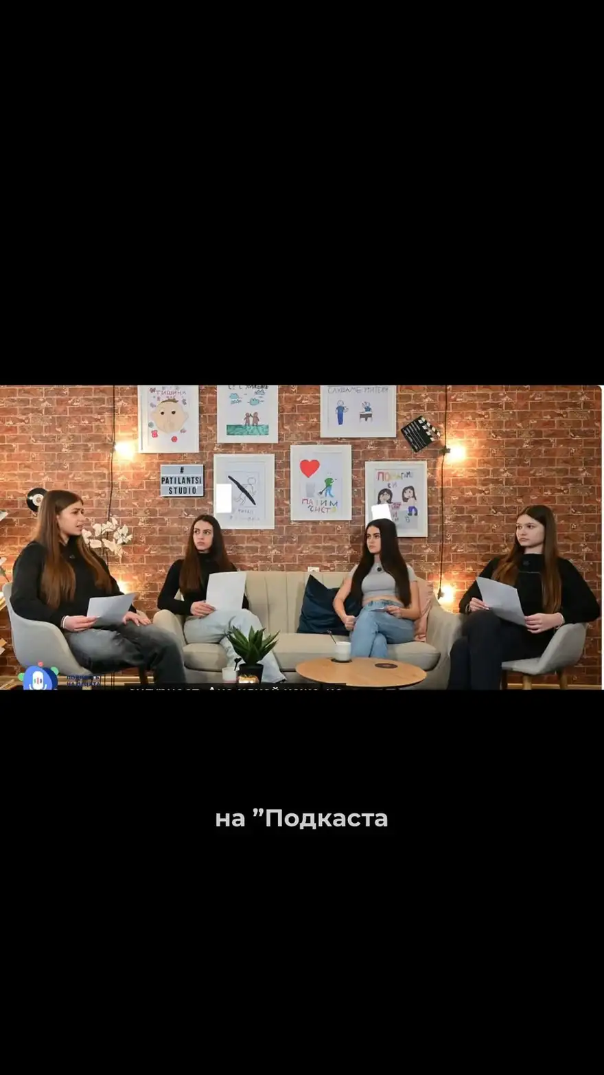 Кадър от епизод: четири участнички седят в кръг пред стена с рисунки.